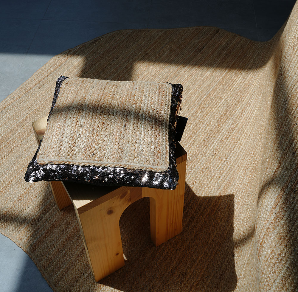Braided rug with braided cushion featuring black fabric border on stool