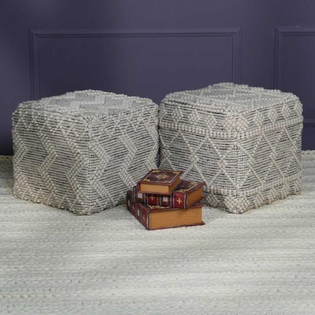 Two woven rugs with three stacked books in front of a white pouf
