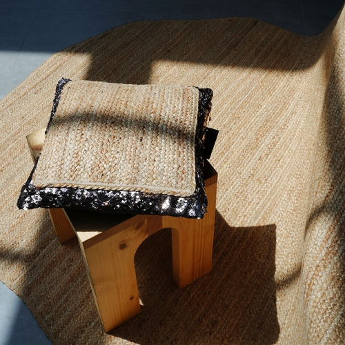 Braided rug with braided cushion featuring black fabric border on stool
