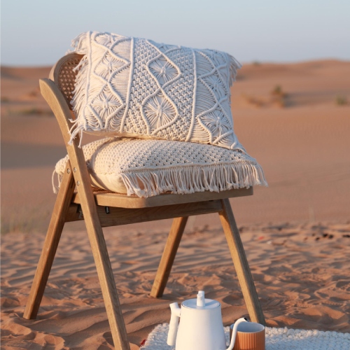Handwoven cushion placed on a wooden chair in a desert setting with a teapot and cup on a mat