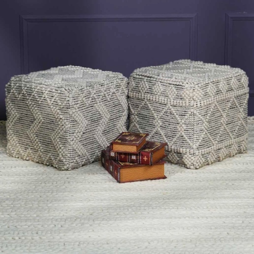 Two woven rugs with three stacked books in front of a white pouf