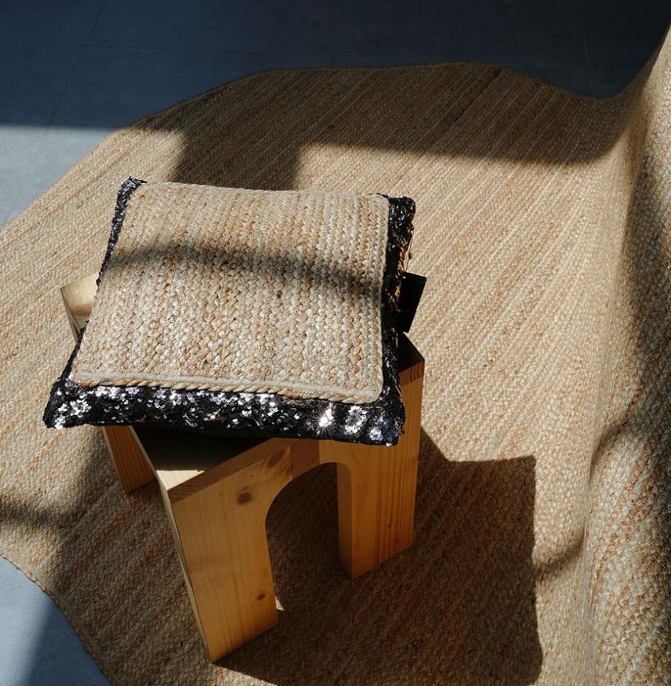 Braided rug with braided cushion featuring black fabric border on stool